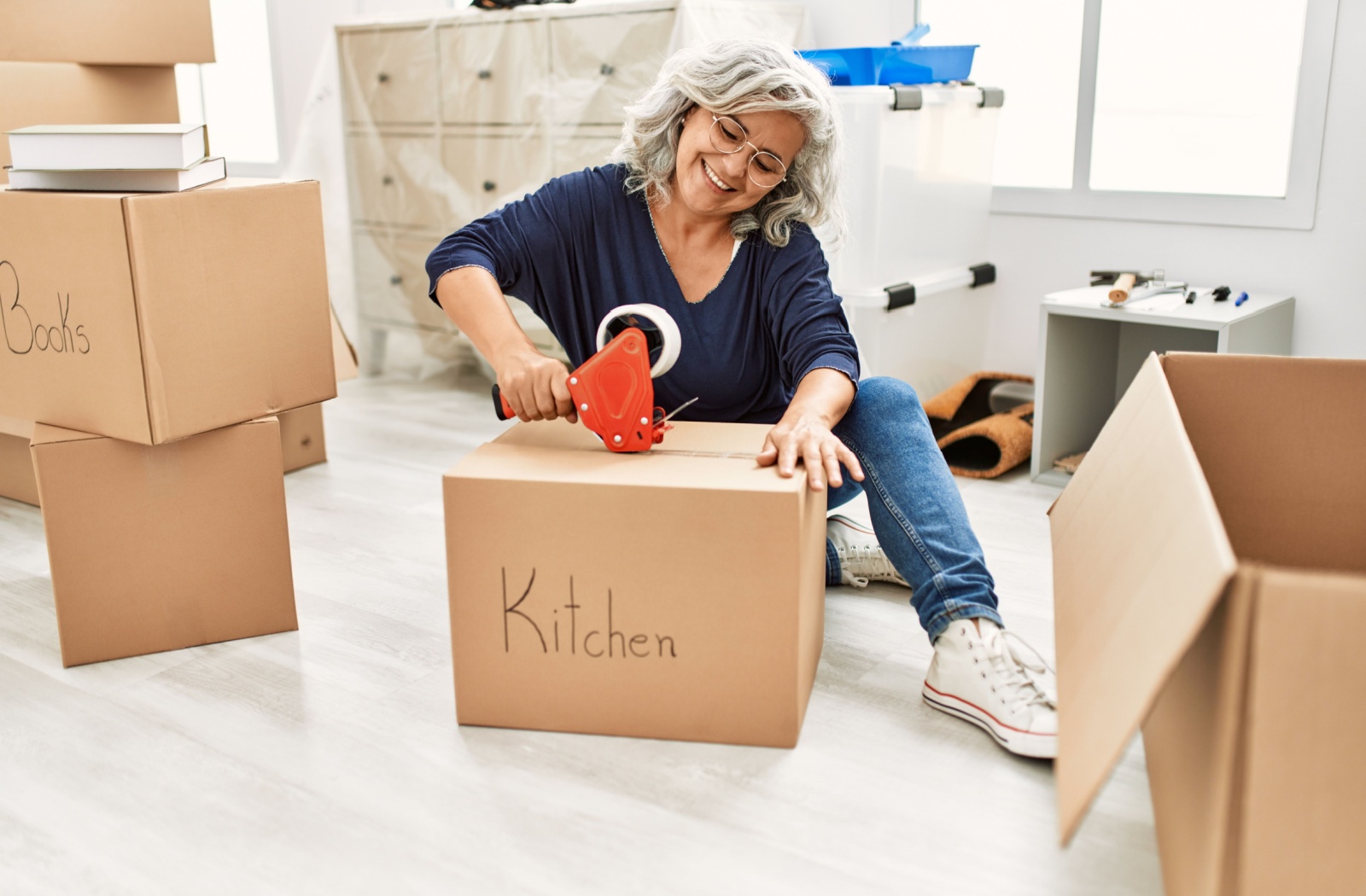 A senior taping up boxes while preparing to move out of their home.