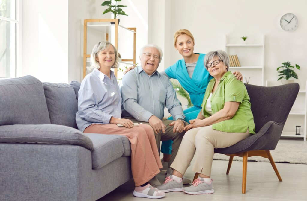 Older adults sitting with a caregiver in a bright memory care community sharing smiles and connection
