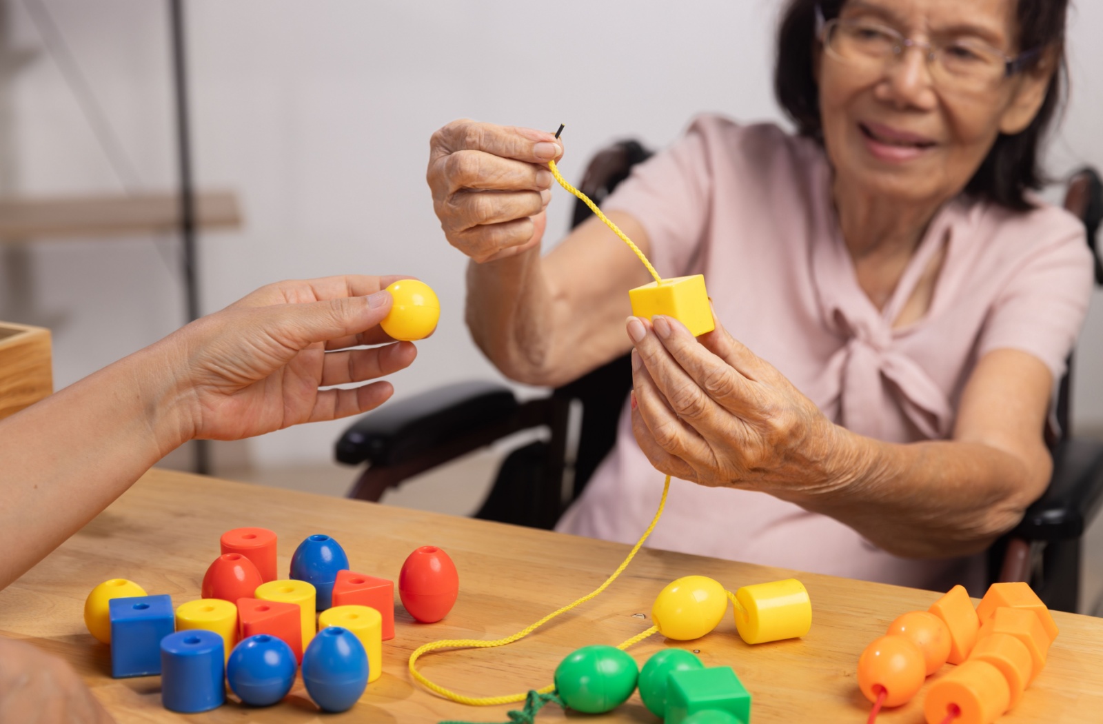 An older adult engages in a memory-building activity with colored blocks of different shapes.
