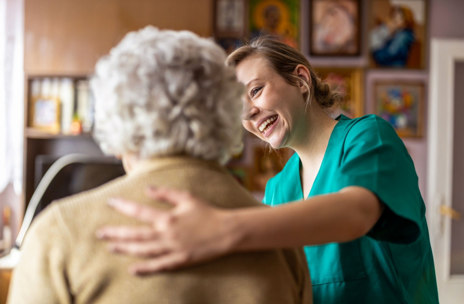 A caregiver puts their arm around a senior resident in memory care.
