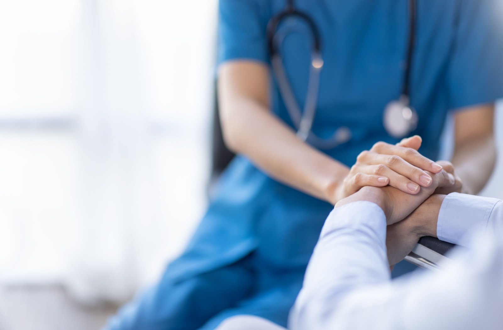 A nurse grasps the hands of a senior resident.