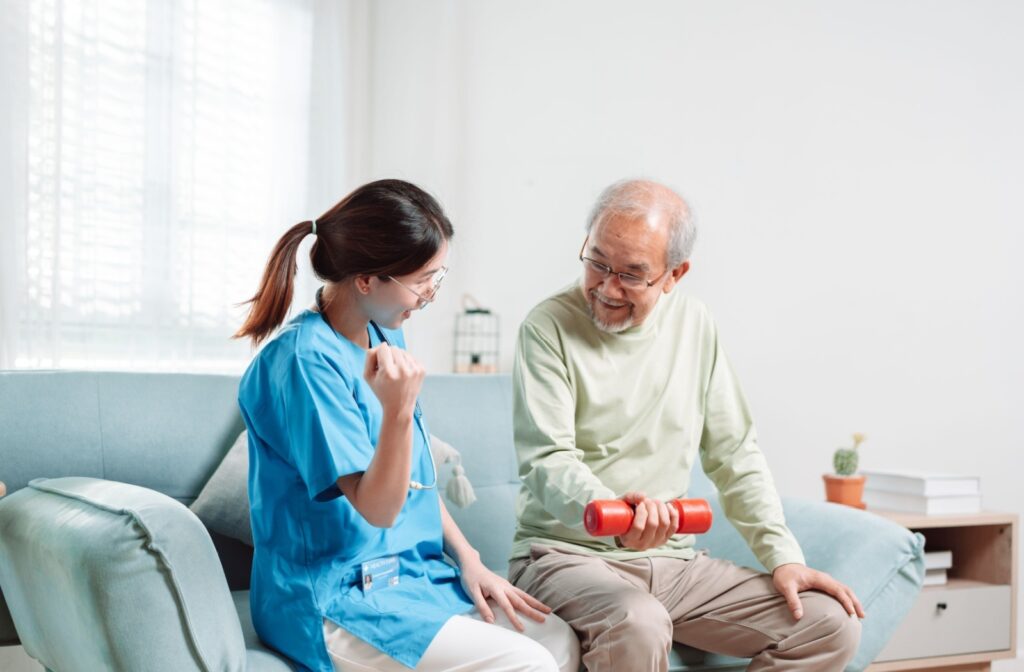 An assisted living resident improves their arm mobility and strength by performing dumbbell curls under the guidance of a caregiver.
